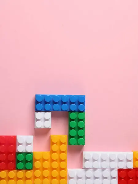 Toy blocks of bricks in the form of a retro video game on a pink background