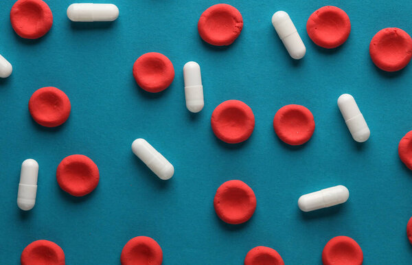 Red blood cells model with pills on blue background. Treatment of blood diseases