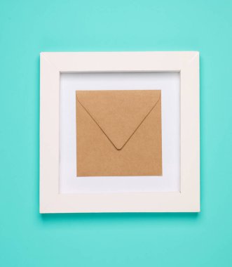 Beyaz kare çerçeveli el işi zarf, mavi arka plan. Estetik asgari natürmort. Kavramsal fotoğraf. Üst görünüm