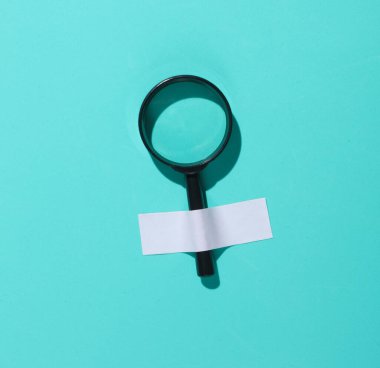 Büyüteç mavi bir duvara bantlanmış. Kavramsal iş fotoğrafı, minimalizm.