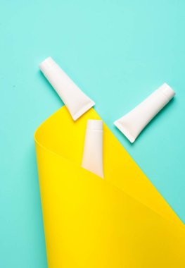 Mavi sarı arka planda beyaz krema tüpleri. Yaratıcı düzen. Üst görünüm