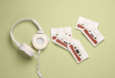 Yeşil arka planda stereo kulaklıklı Retro 80 'lerin ses kaseti. Üst Manzara. Düz yatıyordu