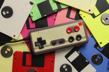 Birçok renkli disketin arka planında eski joystick var. Retro teknolojisi. Üst görünüm