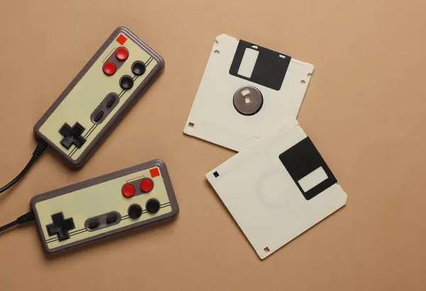 stock image Two retro joysticks and floppy disks on a brown background. Top view