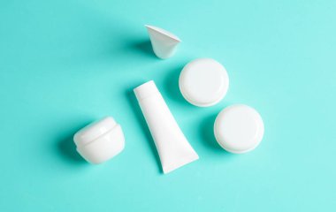 Mavi arka planda beyaz krema kavanozları ve tüpleri. Model, tasarım şablonu. Üst görünüm