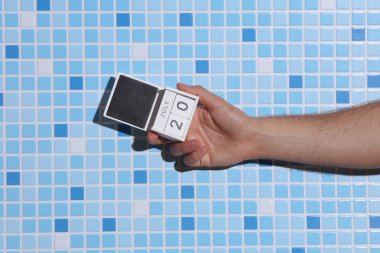 20 Temmuz tarihli ahşap blok takvimi tutan adamın eli fayans zemininde