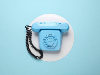 Mavi arka planda beyaz daireli mavi renkli döner telefon. Üst Manzara. Minimalizm