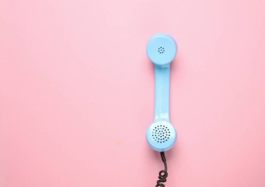 Pembe arka planda, Retro Blue telefon alıcısı. Pastel renk eğilimi. Minimalizm