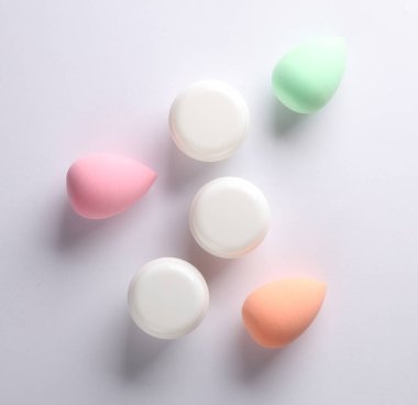 Beyaz arka planda beyaz krema kavanozları ve makyaj süngeri. Güzellik konsepti.