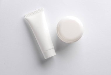 Beyaz arka planda beyaz krema tüpü ve kavanoz. Yaratıcı düzen. Tasarım şablonu. Modelleme. Asgari güzellik kavramı.