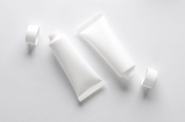 Beyaz arka planda beyaz açık krem tüpleri. Yaratıcı düzen. Tasarım şablonu. Modelleme. Asgari güzellik kavramı.