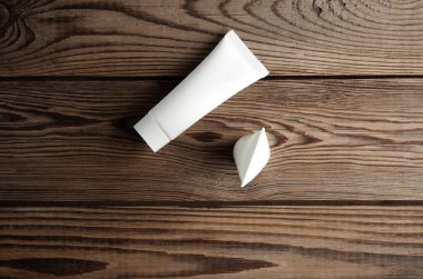 Ahşap arka planda beyaz krema tüpleri. Yaratıcı düzen. Tasarım şablonu. Modelleme. Asgari güzellik kavramı.