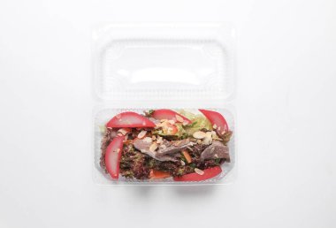 Beyaz arka planda plastik kutuda salatalar. Tekaway yemeği. Üst görünüm