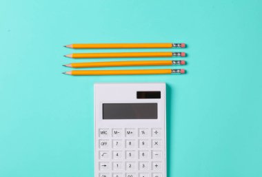 Hesap makinesi ve mavi arka planda bir çift kağıt kalem. iş kavramı