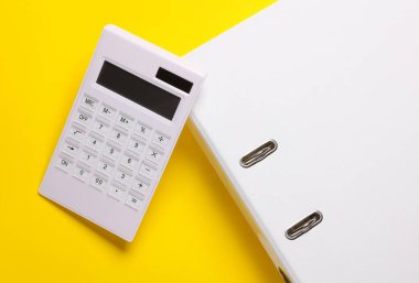 Sarı arka planda klasörü olan hesap makinesi. İş konsepti. Üst görünüm