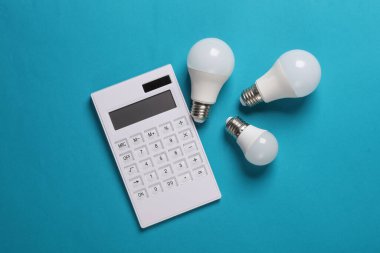 Mavi arka planda kurşun ampulleri olan bir hesap makinesi. Enerji tasarrufu