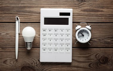 Ampullü hesap makinesi, çalar saat ve tahta arka planda kalem. Yaratıcı bir fikir. Üst Manzara. Düz yatıyordu