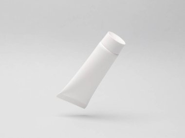 Beyaz krem tüpü gri bir arka planda anti-yerçekimsel havada yükseliyor. Model, tasarım şablonu