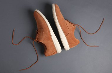 Gri arka planda bağcıkları çözülmüş erkek süet ayakkabıları.