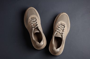 Koyu gri arka planda bej koşu ayakkabıları. Üst görünüm