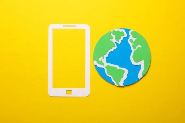 Sarı arkaplan üzerinde küre bulunan kağıt kesimli akıllı telefon simgesi