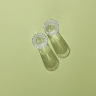 Yeşil arka planda gölgesi olan kristal kadehler. Estetik, trend natürmort, minimalizm. Üst görünüm