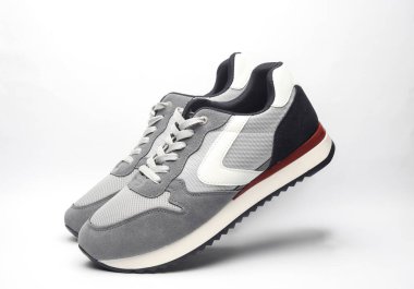 Beyaz arka planda yükselen gri koşu ayakkabıları.