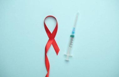 Kırmızı AIDS Farkındalık Kurdelesi ve Mavi Arkaplanda Şırınga