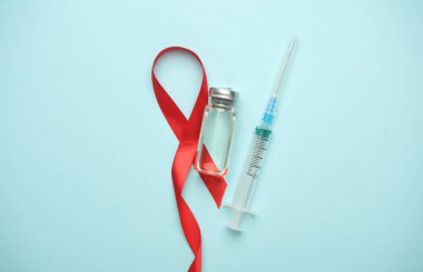 Kızıl AIDS Farkındalık Kurdelesi ve şırınga, Aşı tüpü mavi arka planda