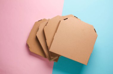 Pembe mavi arka planda bir yığın pizza kutusu. Üst görünüm