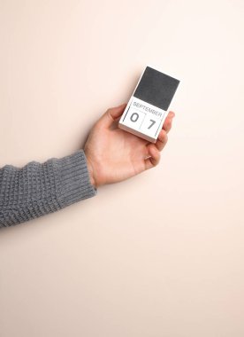 Süveter giymiş bir adamın elinde, takvimde bej bir arkaplanda 7 Eylül tarihi var.