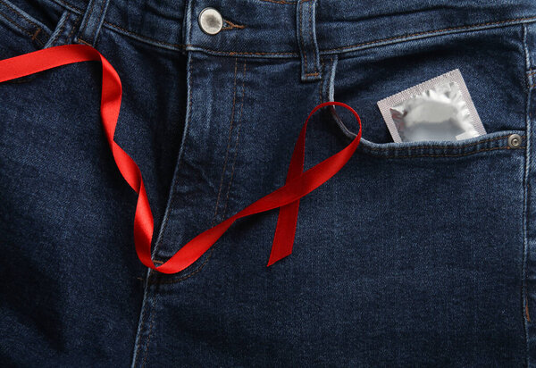 Condom in jeans pocket and Red AIDS Awareness Ribbon