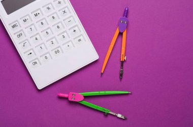 Mor arkaplanda pusulaları olan beyaz hesap makinesi klavyesi