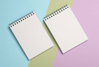 Pastel arka planda iki beyaz boş not defteri.