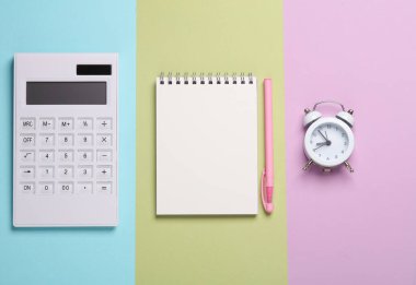 Pastel arka planda hesap makinesi, defter ve çalar saat. Okul malzemeleri. Üst görünüm
