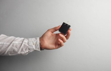 Beyaz gömlekli adamın elinde gri arka planda minyatür bir alışveriş çantası var. Kara Cuma, dünya alışveriş günü, satış konsepti