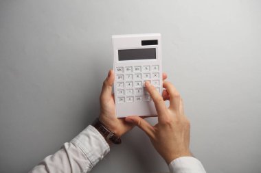 Gri arka planda hesap makinesi kullanan erkek eller. İş konsepti