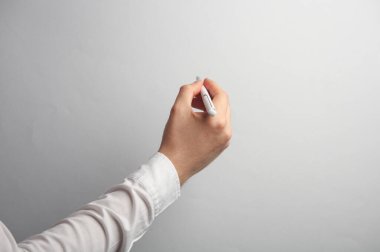 Beyaz gömlekli adamın eli gri arka planda kalem tutuyor. Tasarım için maket. İş konsepti