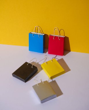 Sarı arka planda minyatür kağıt alışveriş torbaları. Kara Cuma, dünya alışveriş günü, tatil indirimi konsepti.