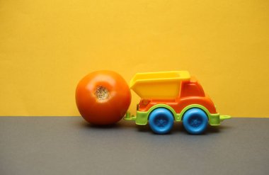 Sarı arka planda domatesli oyuncak kamyonu.