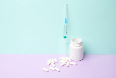 Pastel arka planda şırıngalı haplar.