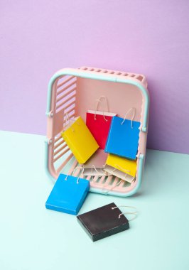 Pastel arka planda süpermarket sepetinde minyatür alışveriş torbaları. Kara Cuma, dünya alışveriş günü, indirim.