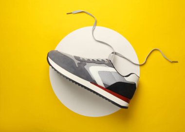 Beyaz dairelerde gri bir spor ayakkabı. Sarı arka plan. Yaratıcı bir fikir. Moda konsepti. Üst görünüm