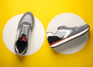 Beyaz dairelerde gri spor ayakkabılar. Sarı arka plan. Yaratıcı bir fikir. Moda konsepti. Üst görünüm