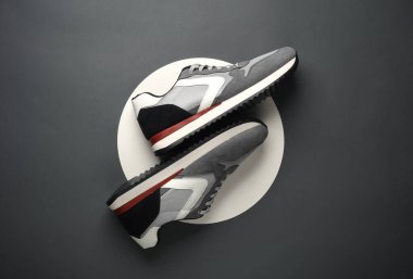 Beyaz dairelerde gri spor ayakkabılar. Gri arka plan. Yaratıcı bir fikir. Moda konsepti. Üst görünüm