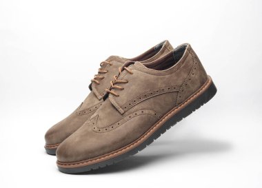 Beyaz arka planda havada asılı deri ayakkabılar.