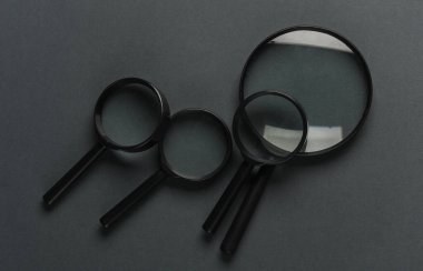 Koyu gri arka planda büyüteçler. Üst görünüm