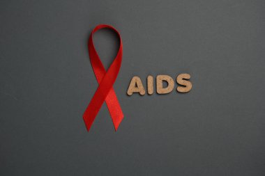 Koyu arkaplanda kelime yardımcıları olan kırmızı farkındalık kurdelesi. Dünya HIV Yardım Günü 