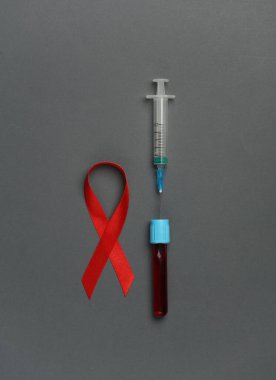 Koyu arkaplanda kan testi tüpü olan kırmızı farkındalık kurdelesi. Dünya HIV Yardım Günü 