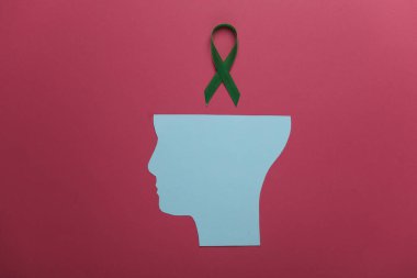 Pembe arka planda kağıt kesikli yeşil farkındalık kurdelesi. Dünya Ruh Sağlığı Günü konsepti